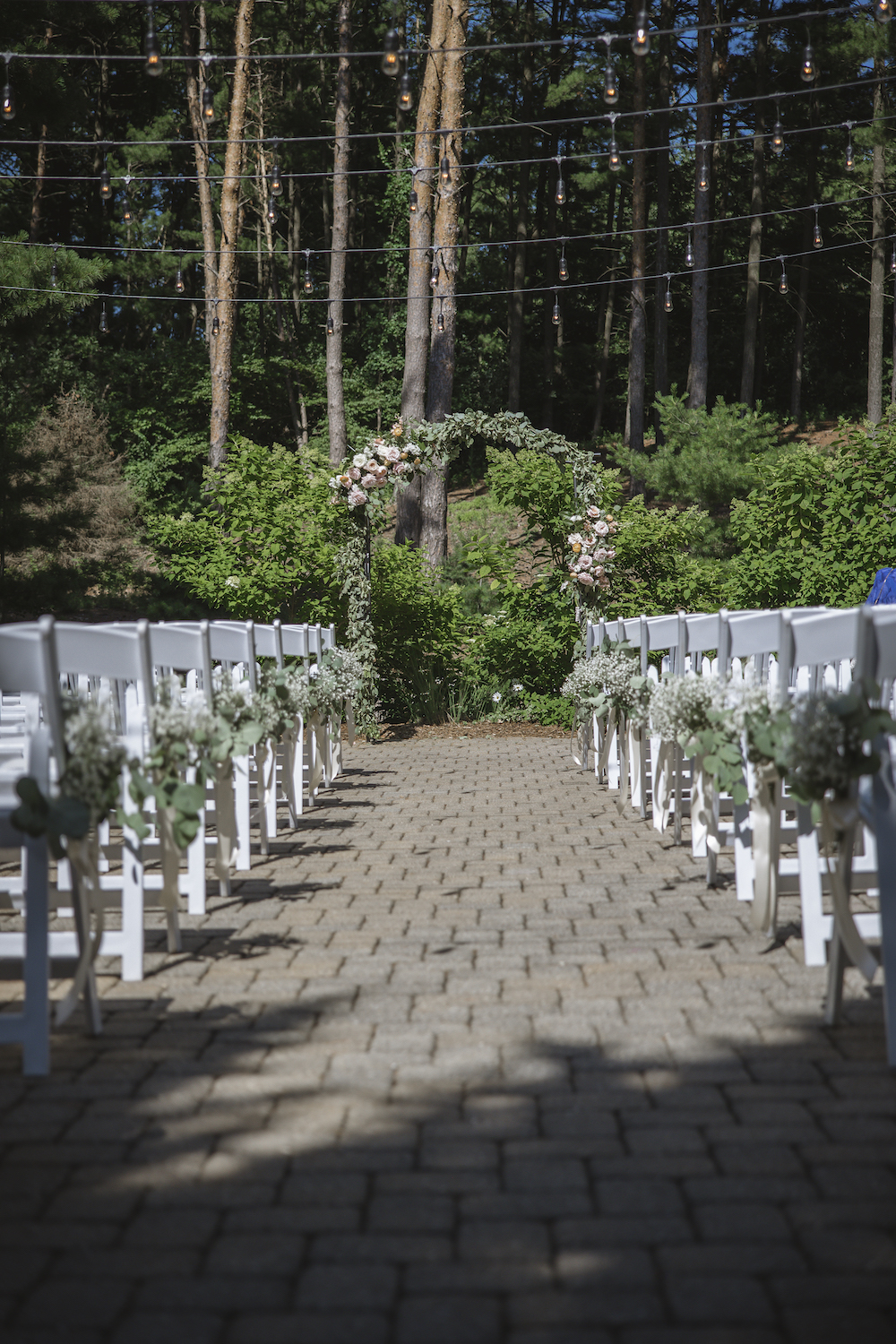 Wedding ceremony venue with rows of white chairs and a wedding arch at the end of the aisle, taken by Green Holly Photography